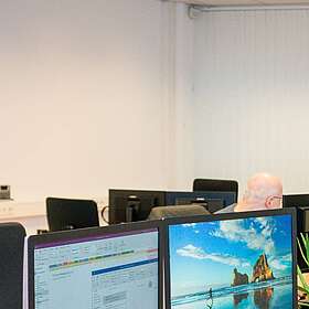 Mitarbeiter sitzen an ihren Arbeitsplätzen und arbeiten.