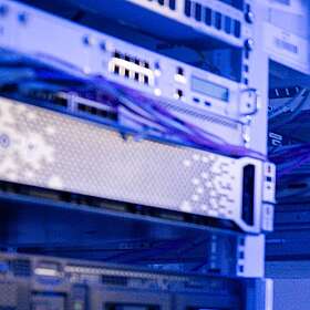 Ein Mann steht im Serverraum. Er überprüft die Kabel. 